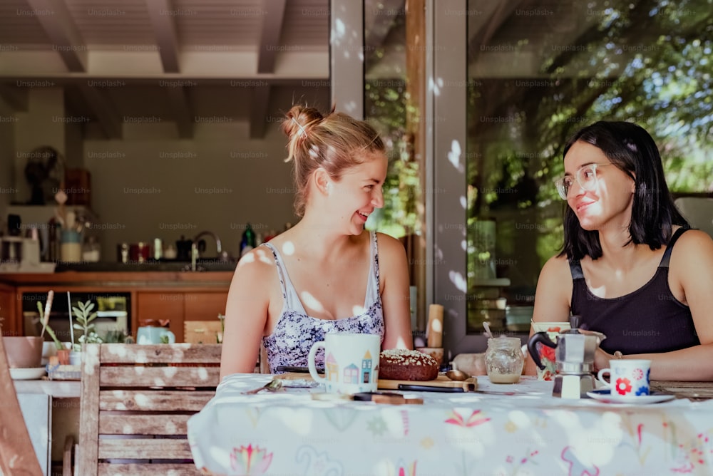 Dos mujeres sentadas en una mesa conversando