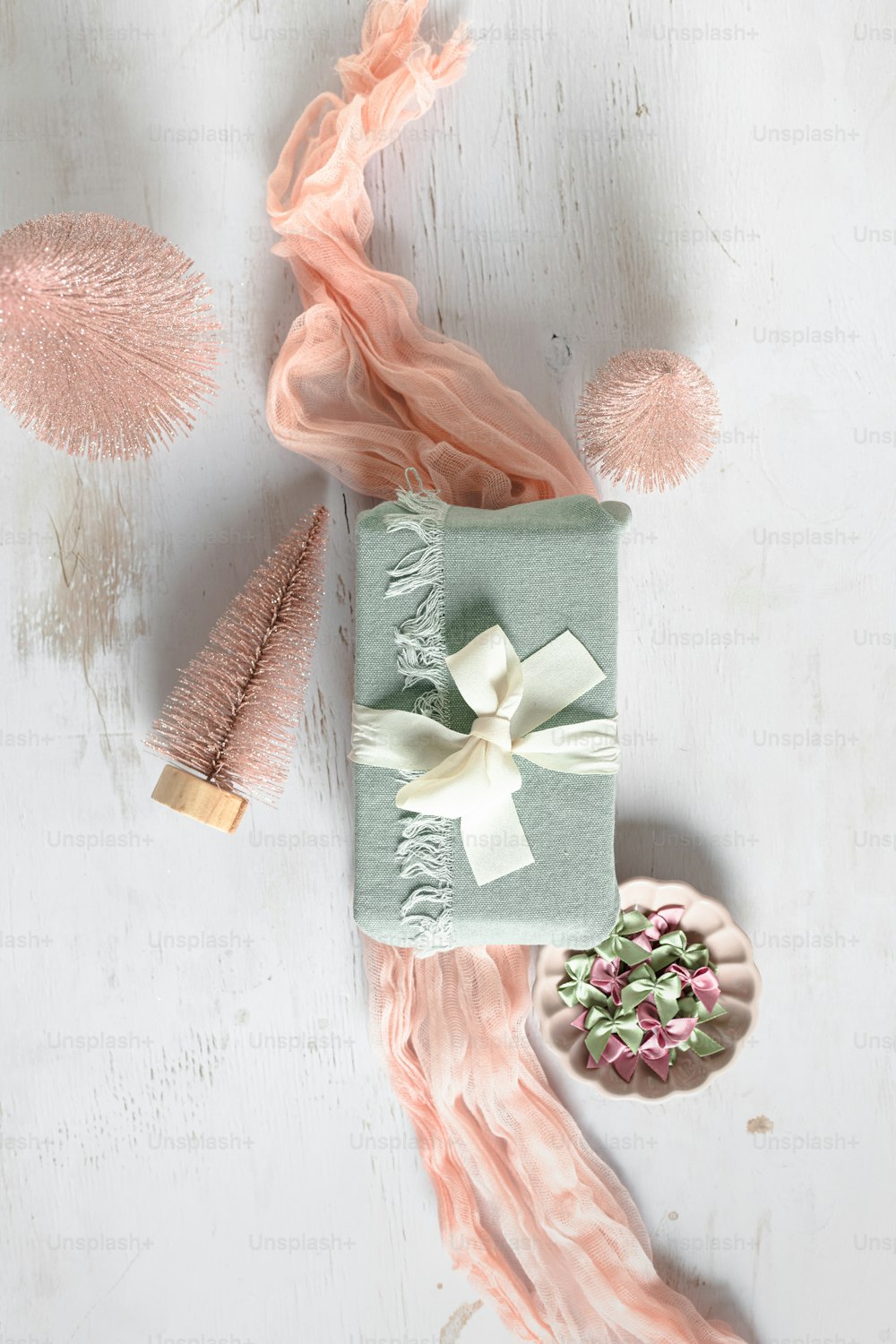 a gift wrapped in pink tissue next to a pink pom - pom