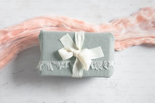 a wrapped gift with a white ribbon on a white table