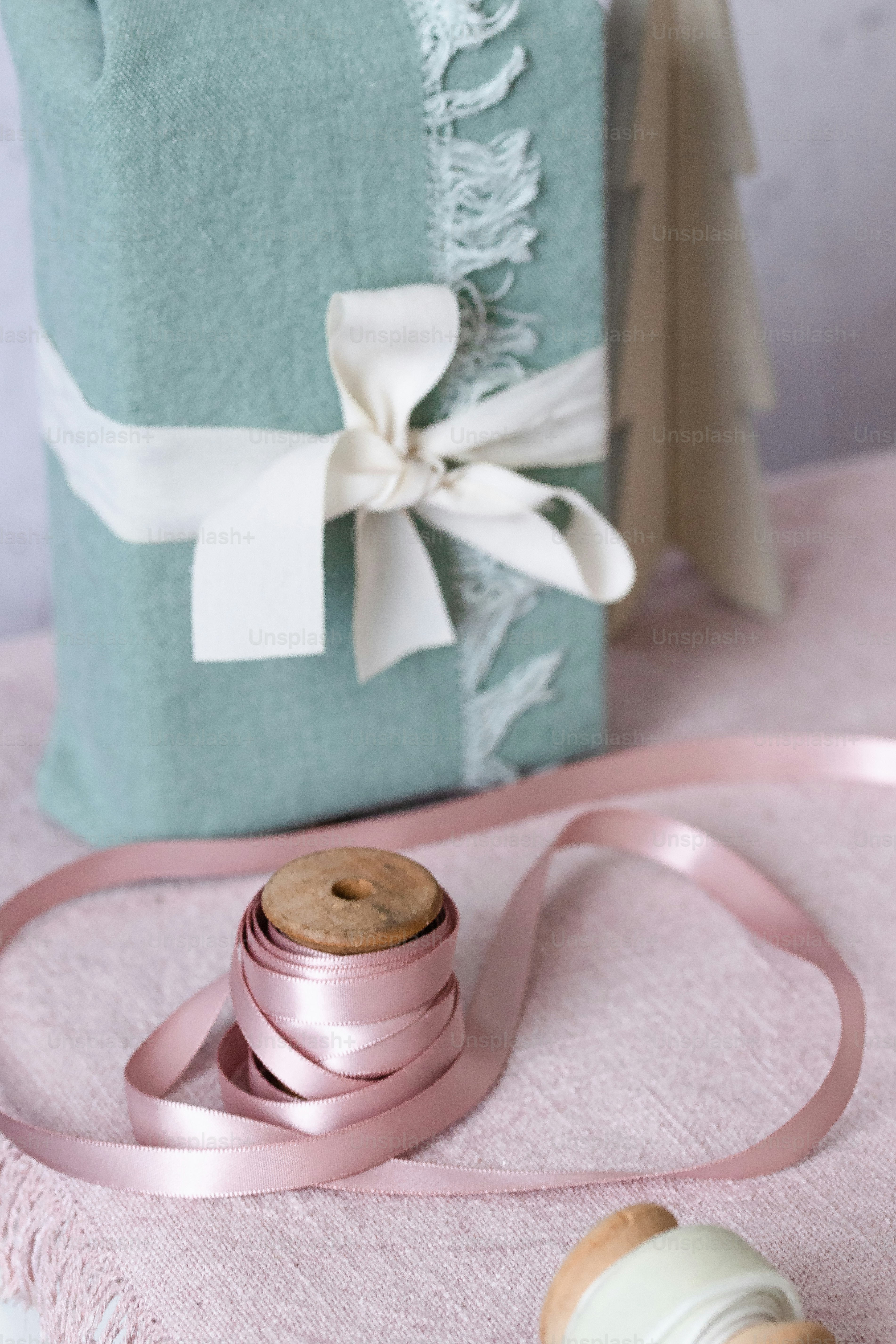 A roll of pink ribbon sitting on top of a table next to a bottle of ...