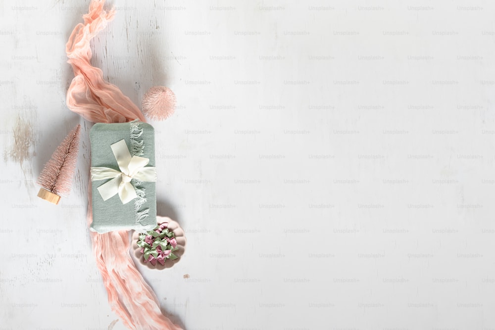 Una mesa blanca con un regalo y un arreglo floral