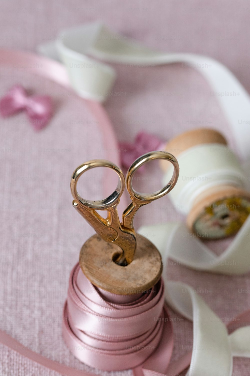 a pair of scissors sitting on top of a pink ribbon