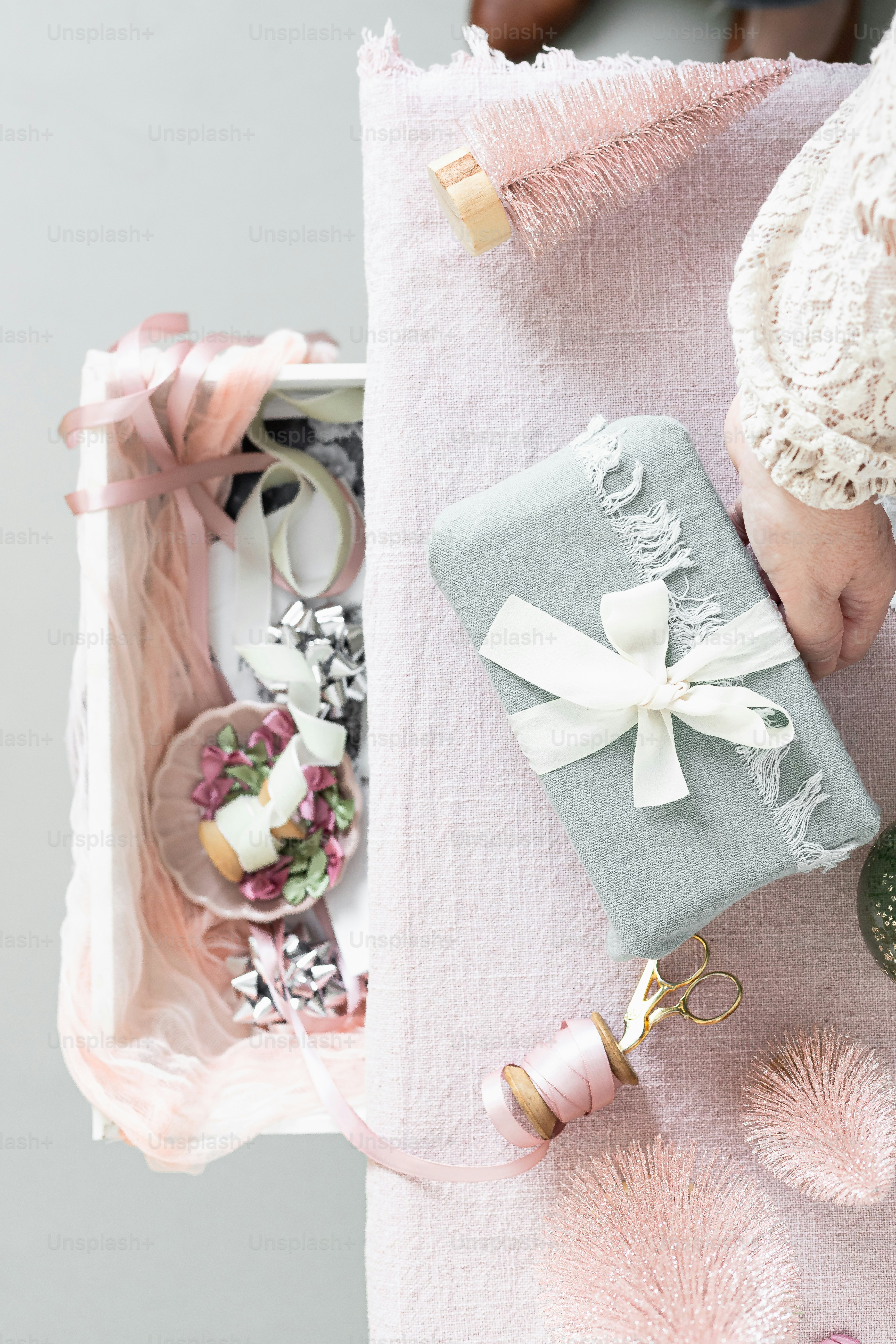 a baby's hand is holding a gift wrapped in a pink ribbon