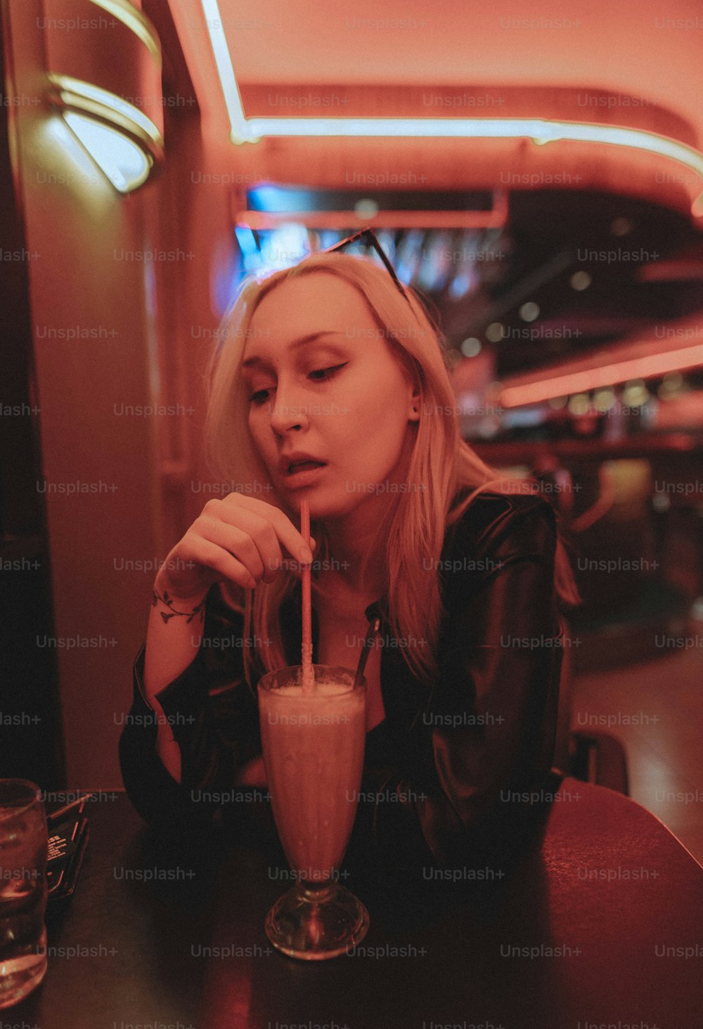 uma mulher sentada em uma mesa bebendo uma bebida
