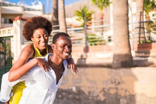 beautiful young african race couple enjoy and have fun together in the summer day of vacation. happy lifestyle with love and friendship for black man and woman. the man carry the woman on his back