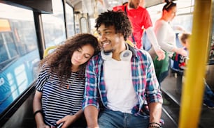 Cute curly girl is leaning on her boyfriend in a bus.