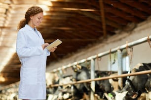 Joven granjera con panel táctil en busca de información sobre enfermedades de vacas