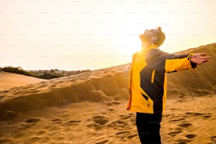 middle age man enjoying freedom and exploring leisure activity opening arms and hugging the nature. desert arid place for alternative lifestyle and vacation time. summer and sunset with backlight. golden colors