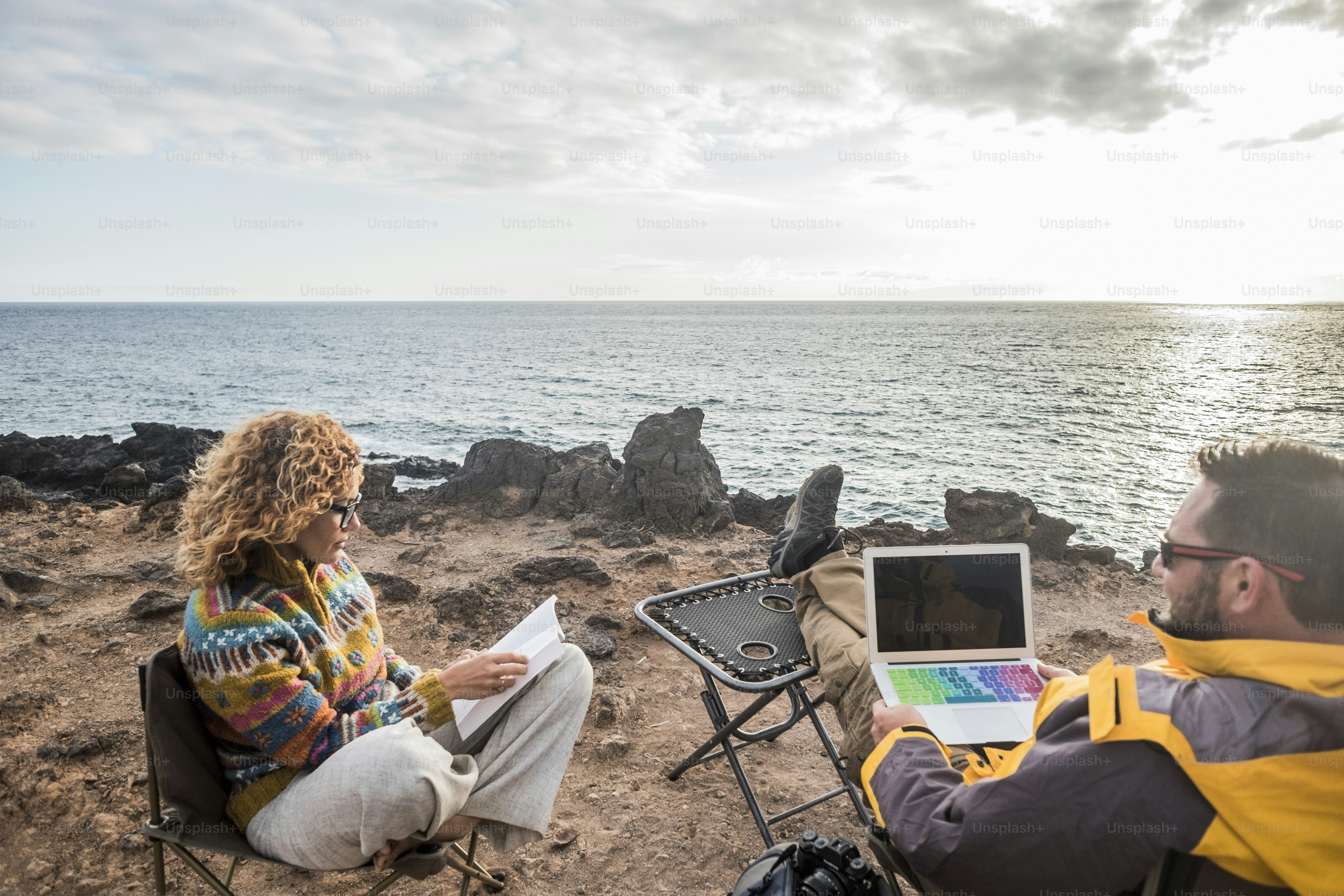 nice couple enjoying a sunset at the end of the day. travel lifestyle in wanderlust for happy cacucasian people. working alternative office with laptop and mobile connection to internet. photographers and tourist
