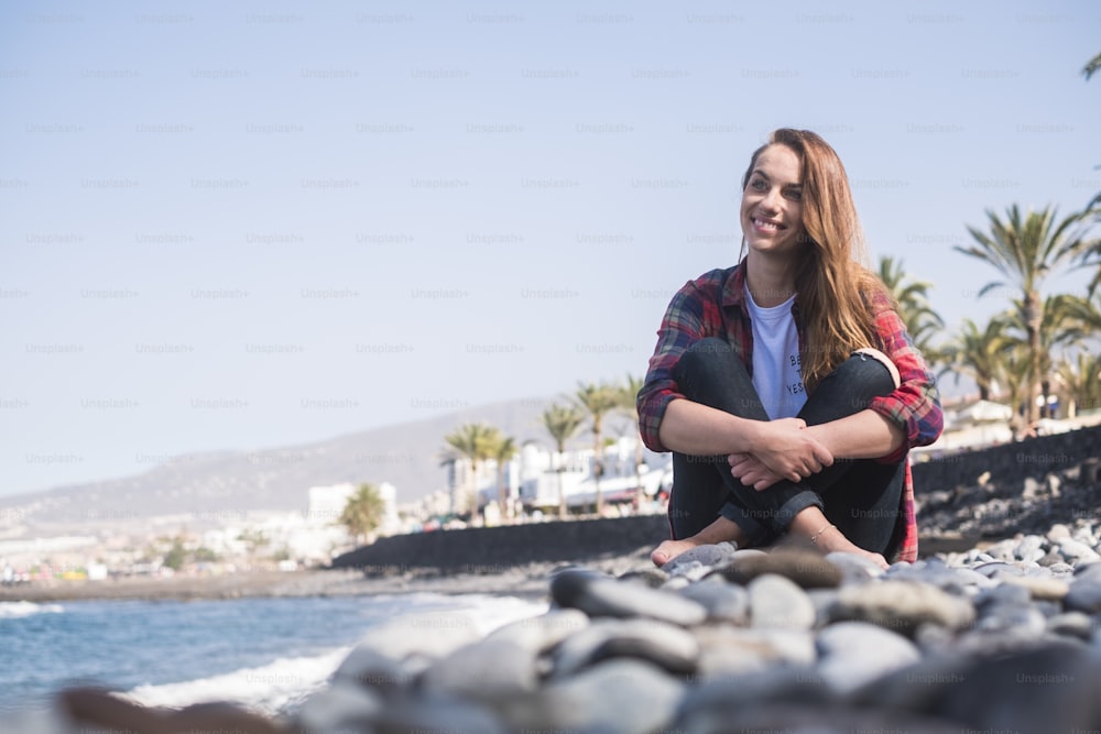 nice beautiful young caucasian woman enjoy and have fun at the beach in summer holiday. vacation concept for female traveler in trendy hipster clothes. ocean in background