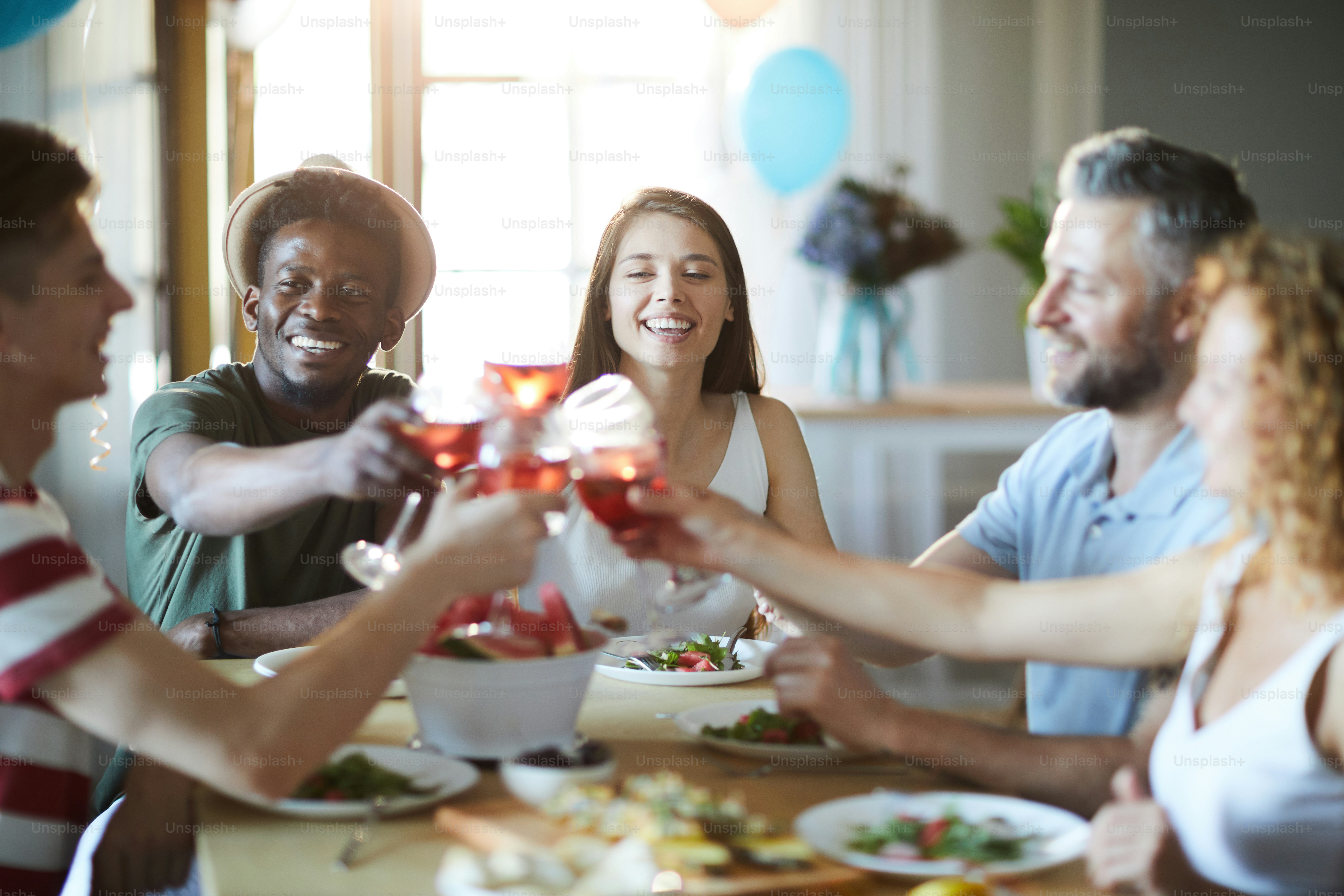 Happy intercultural friends gathered by table for holiday celebration at home