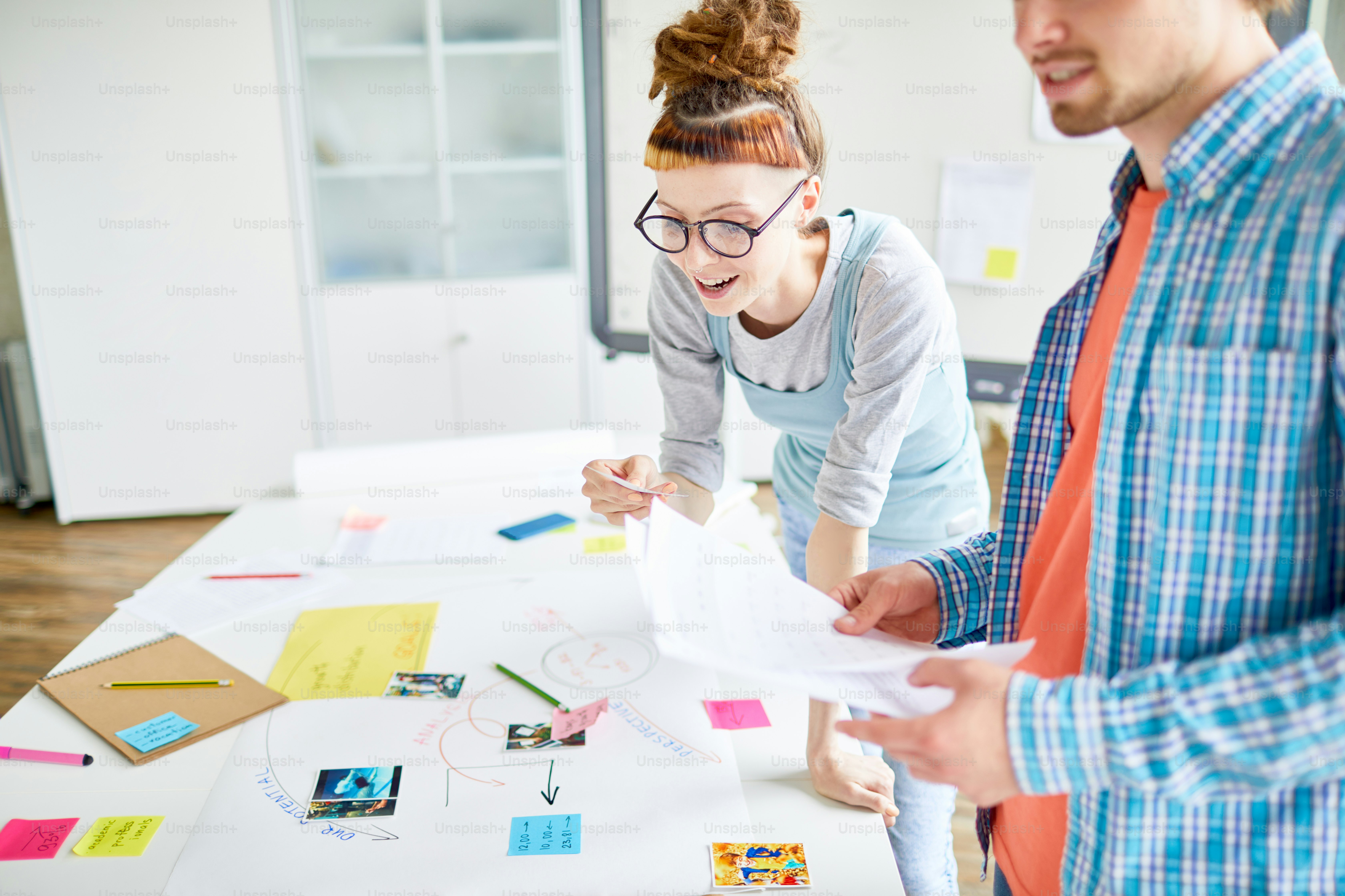 Uno degli studenti che guarda l'immagine mentre si sporge sul tavolo e discute le idee per il progetto con il compagno di gruppo
