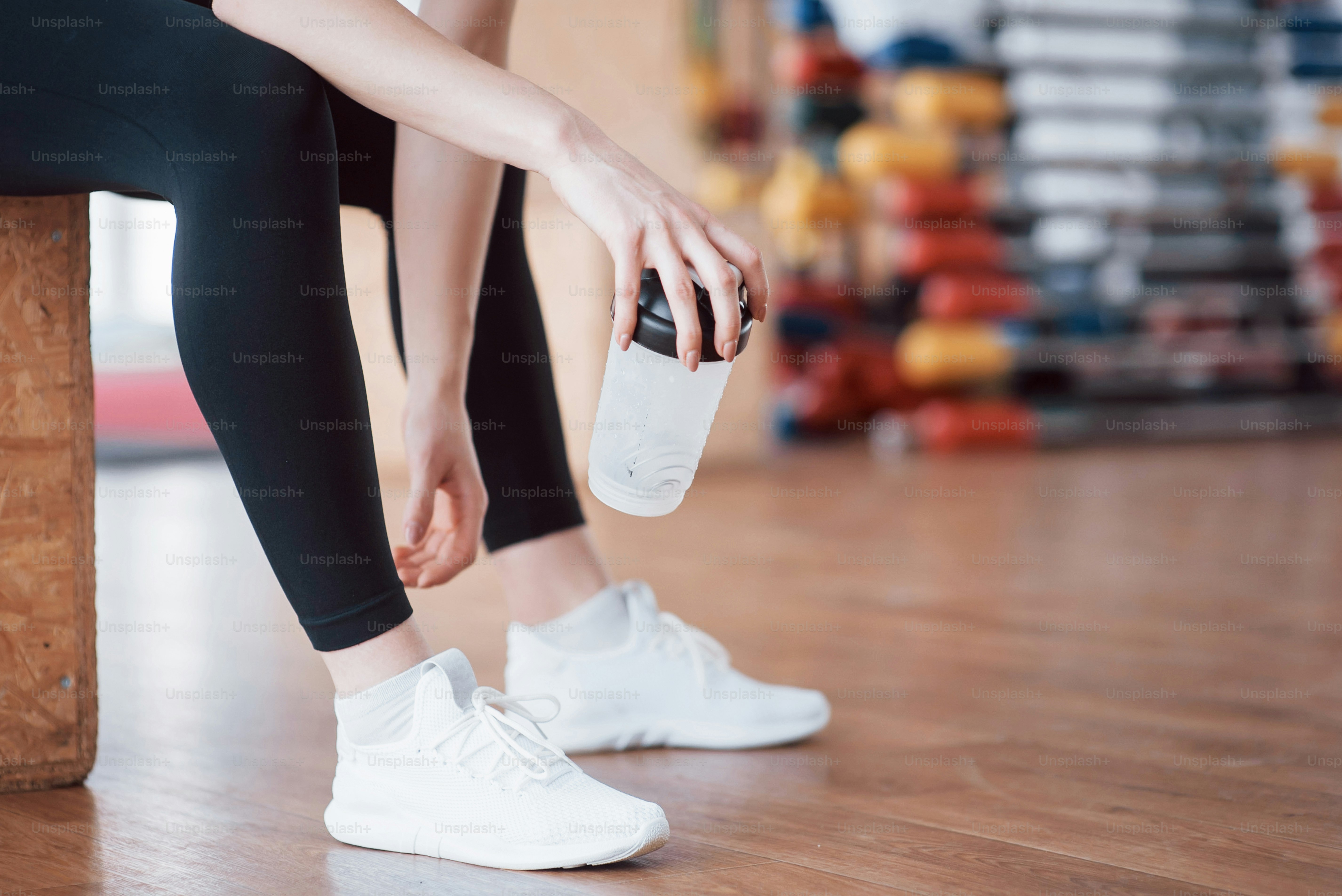 Se détendre après l’entraînement. Vue rapprochée d’une belle jeune femme assise sur un tapis d’exercice au gymnase.