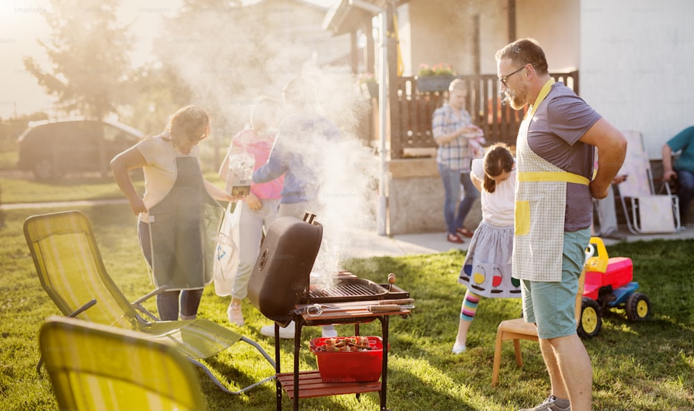Une grande famille heureuse fait un barbecue et profite de vacances dans l’arrière-cour.
