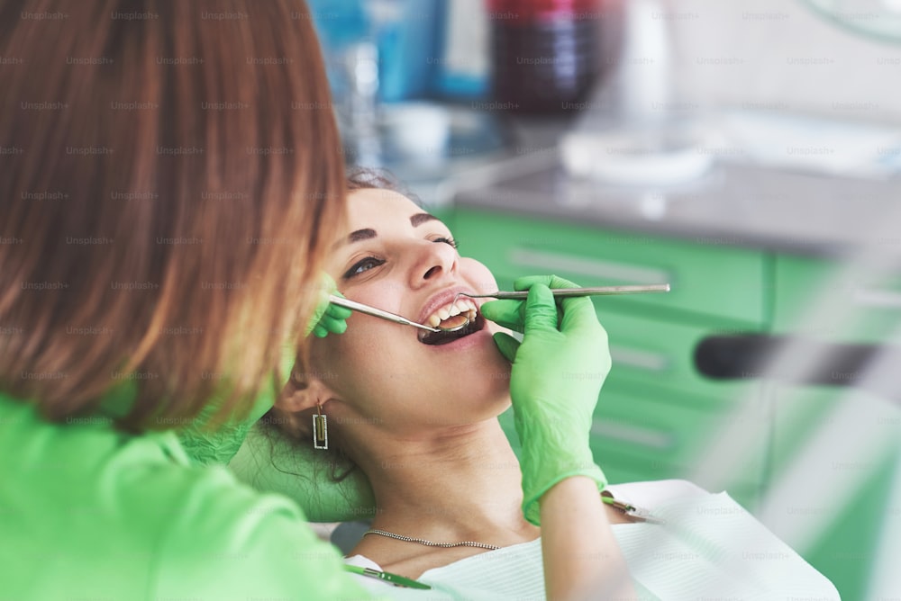 Dentista curando uma paciente do sexo feminino na estomatologia. Conceito de prevenção precoce e higiene bucal.