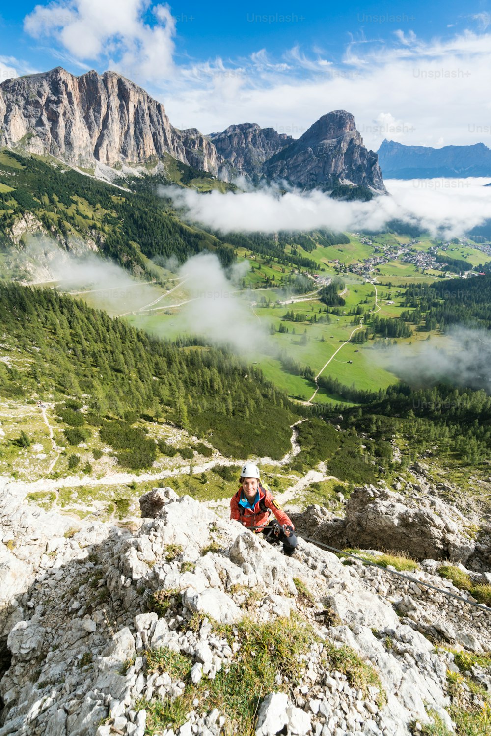 イタリアの南チロル州アルタバディアのドロミテの困難なヴィアフェラータの若い魅力的な女性登山家