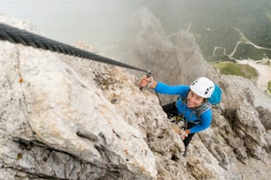 giovane attraente alpinista su una ripida ed esposta via ferrata in Alta Badia in Alto Adige nelle Dolomiti italiane