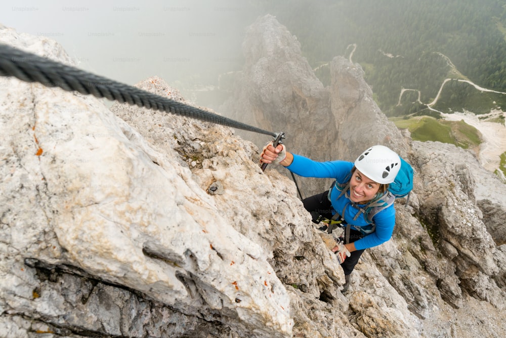 jovem alpinista feminina atraente em uma íngreme e exposta Via Ferrata em Alta Badia, no sul do Tirol, nas Dolomitas italianas