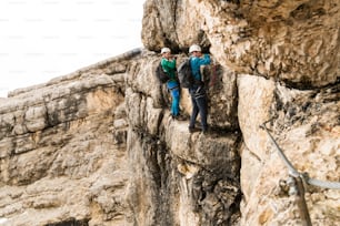 two young attractive male mountain climbers on very exposed Via Ferrata in Alta Badia in the Italian Dolomites