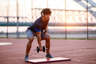 音楽を聴きながら腕に体重を乗せている若いスポーティなフィット感の男性。早朝のトレーニング以外。