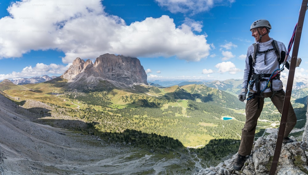 young attractive male mountain climber in the Dolomites of italy with a great panorama view of the Langkofel and Passo Sella