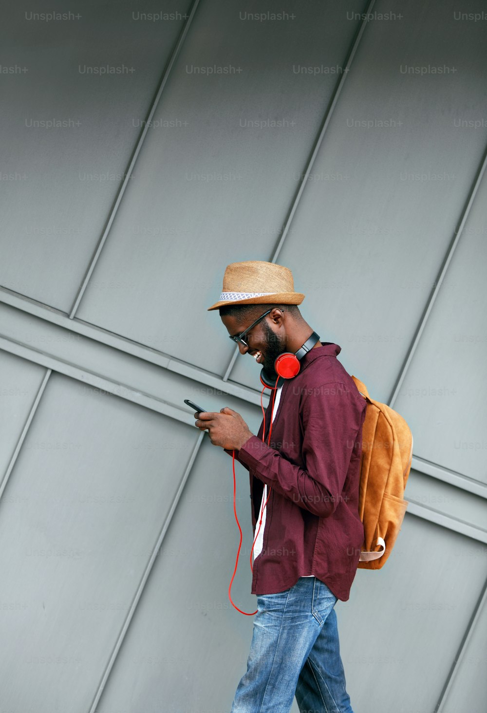 Mode pour hommes. Homme Avec Téléphone Et Écouteurs Dans La Rue. Mâle noir souriant élégant à l’extérieur. Haute résolution