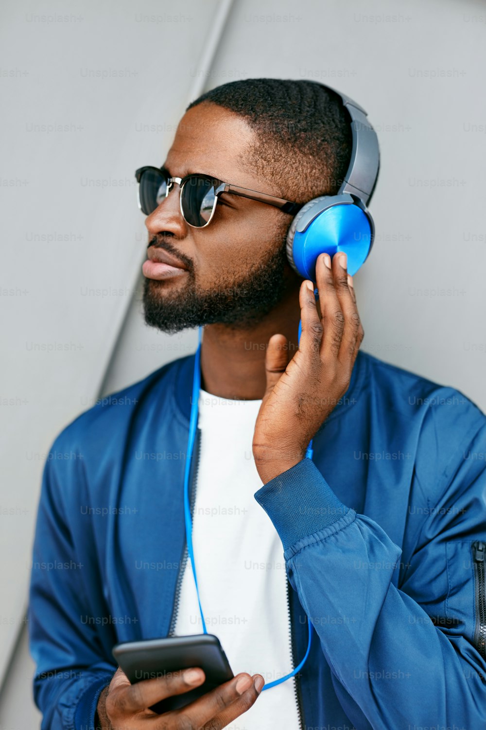 Listen Music. Man With Headphones And Phone In Fashion Clothes. Handsome Black Male Listening Music Outdoors. High Resolution