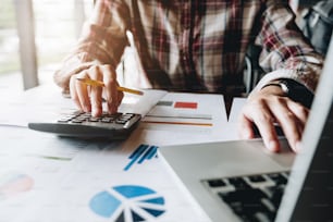 Businessman analyzing investment charts with calculator and laptop computer. Accounting and technology in office,marketting plans.