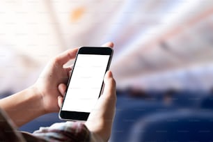 Pasajero de avión usando un teléfono inteligente en el avión. Hombre de negocios tocando el teléfono móvil de la pantalla en blanco en el avión. para el montaje de la visualización de gráficos.