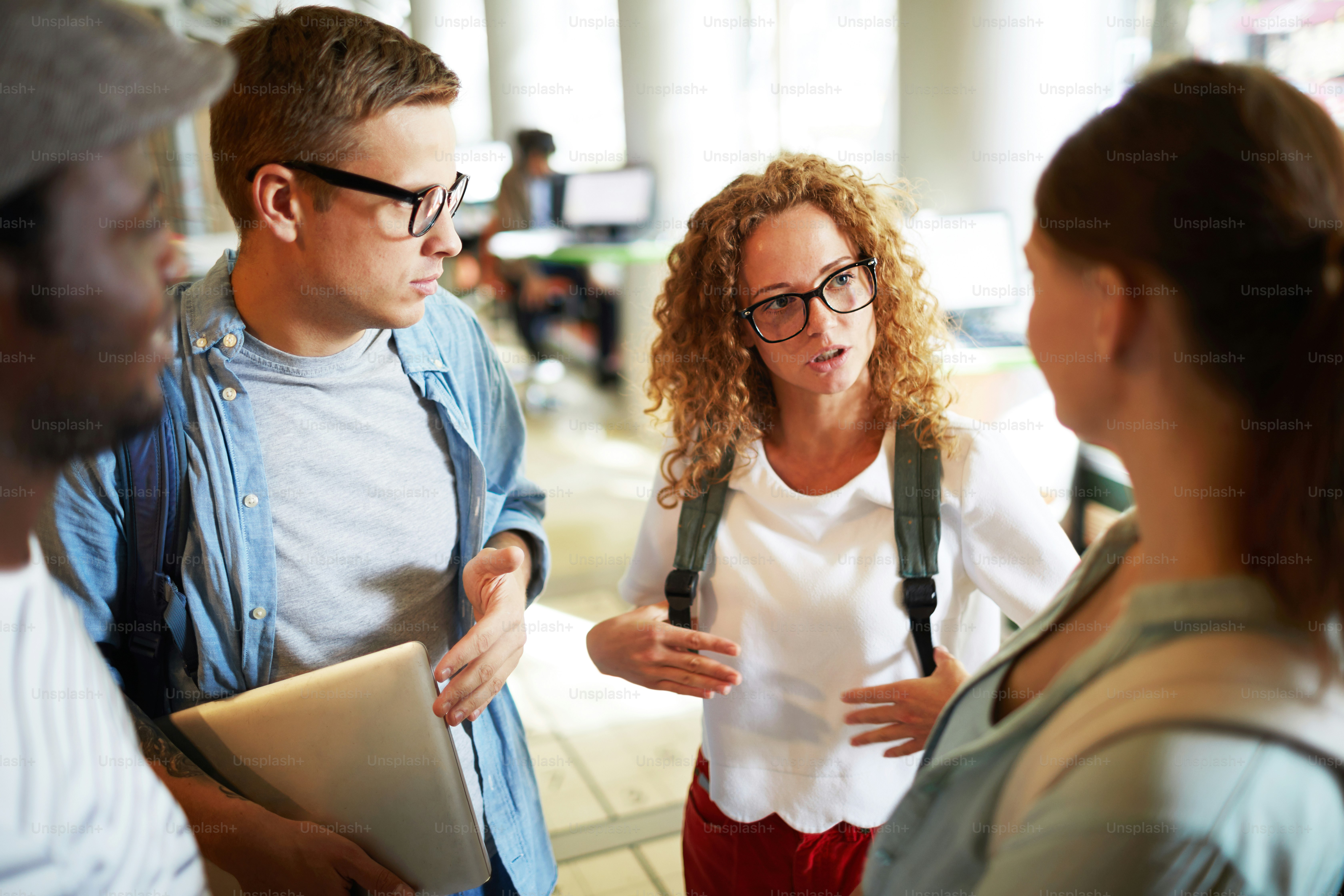 Group of young intercultural girls and guys with backpacks discussing ...
