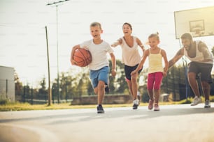 Spring is great for family sport.  Happy family playing basketball outside. On the move.