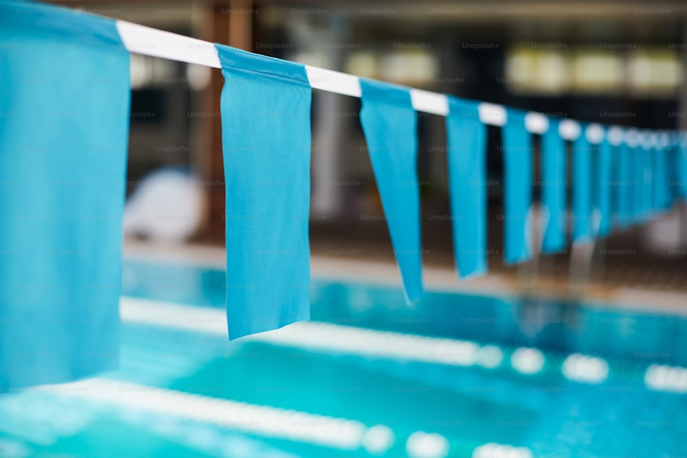 Row of blue flags hanging on white ribbon over swimming-pool as border