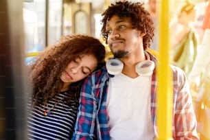 Picture of cute young couple sitting in a bus. Girl leaned her head on boyfriends shoulder.