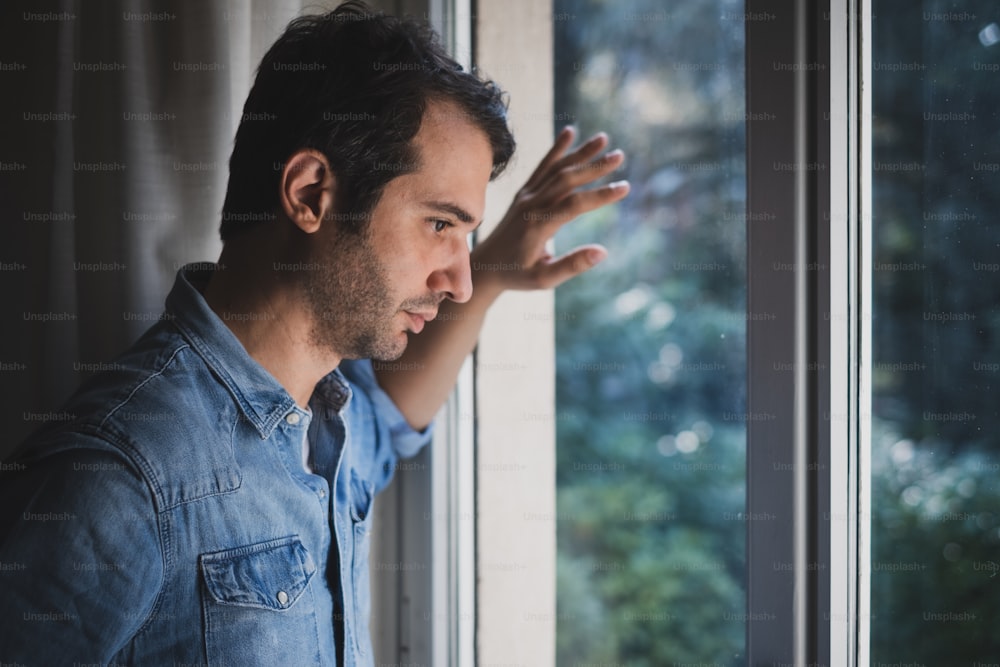 Hopeless man feeling alone and lost looking out window