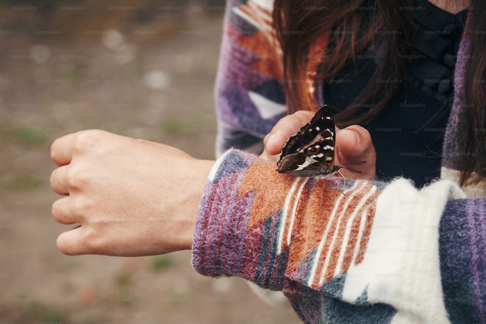 소녀 손에 아름 다운 나비입니다. 산속의 숲에서 손가락에 아파투라 아이리스를 들고 있는 세련된 행복한 여자. 여행과 방랑벽 개념. 텍스트 공간. 놀라운 순간. 우크라이나의 곤충