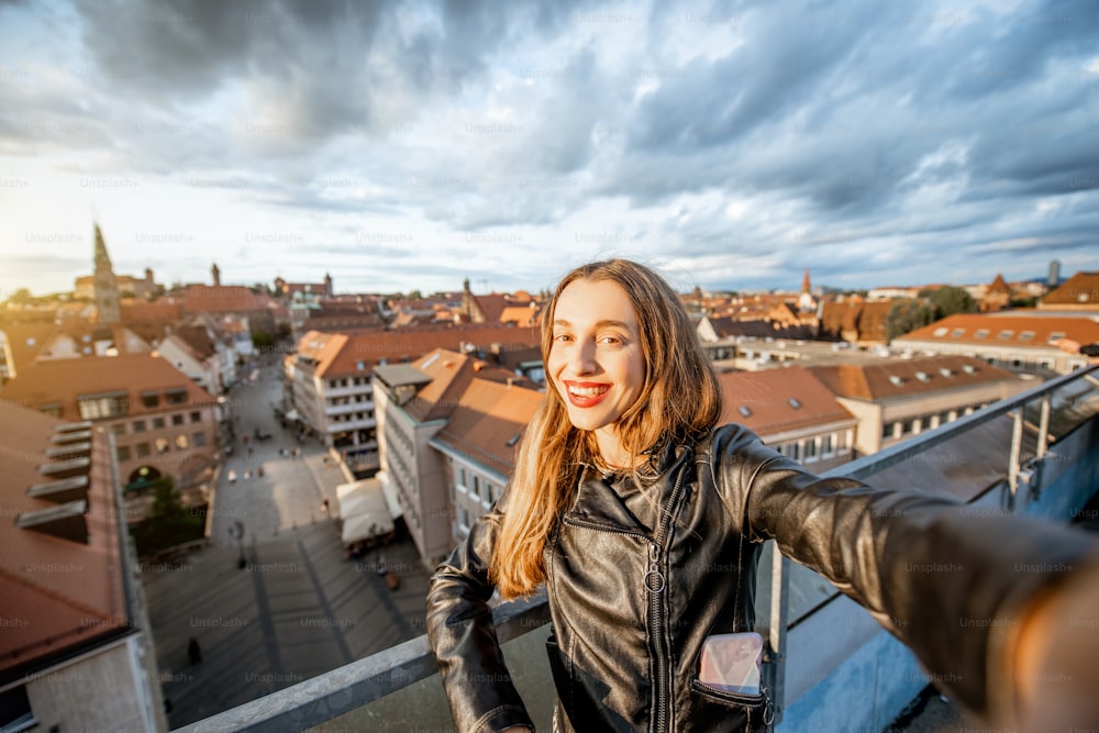 Turista joven y feliz que toma una foto selfie en el fondo del paisaje urbano que viaja en Núremberg, Alemania