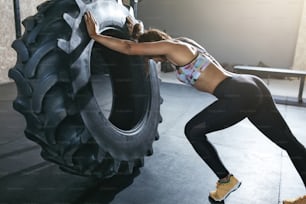 Pesas. Deportista entrenando con rueda en el gimnasio. Atleta femenina que usa la rueda para el entrenamiento físico. Alta resolución
