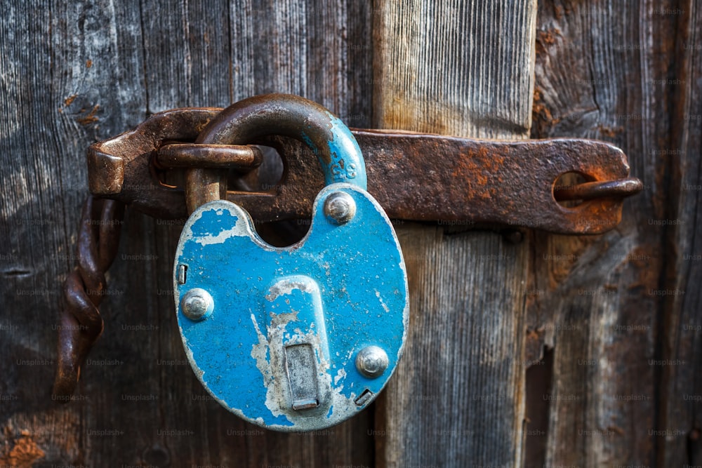 La vieille porte en bois est fermée par un château de grange bleu rouille. Cadenas sur la porte de garage. Porte verrouillée sur le château. Vintage, vieux. Débarras, garage, hangar.serrure ouverte, casse-porte