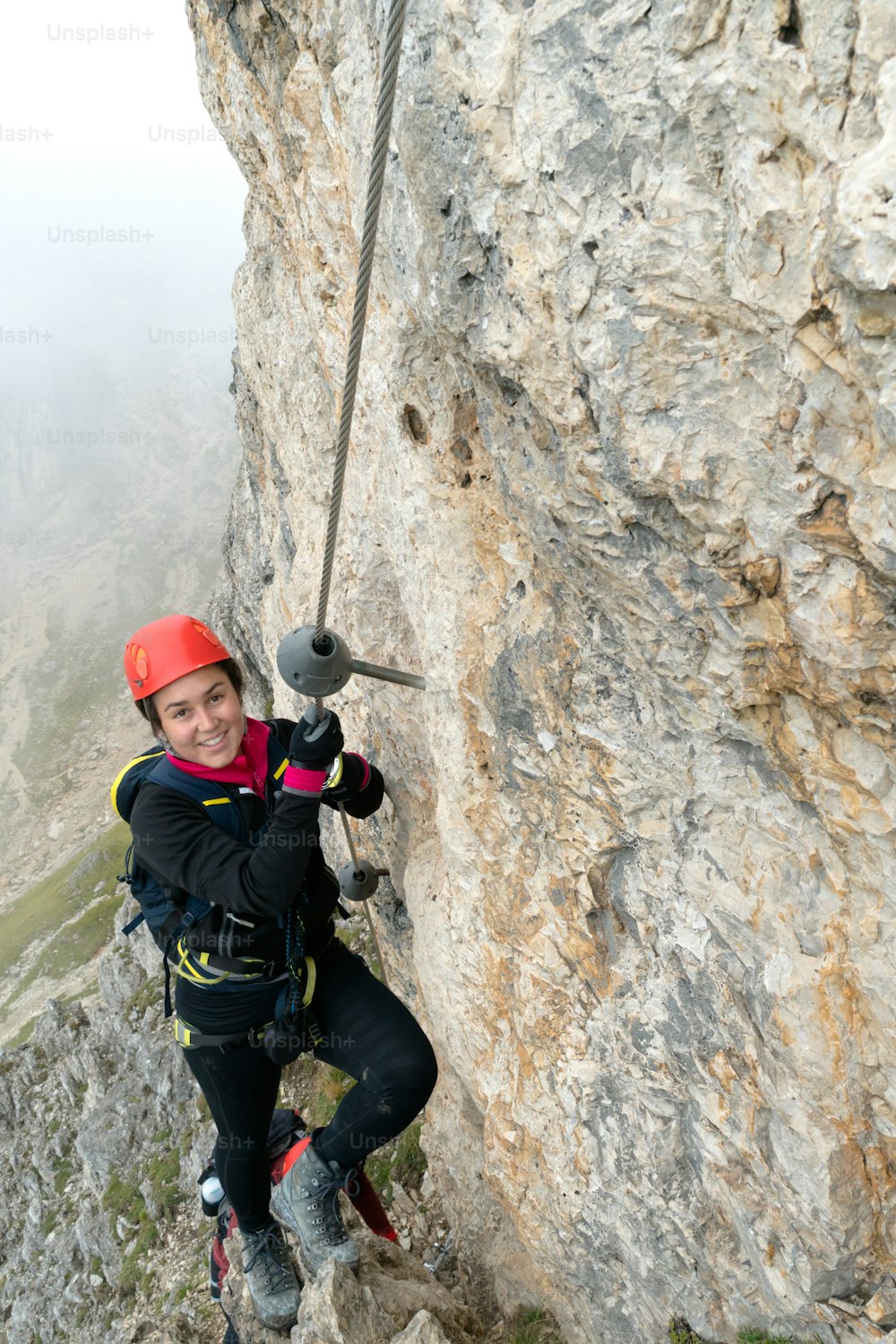 giovane attraente alpinista su una ripida ed esposta via ferrata in Alta Badia in Alto Adige nelle Dolomiti italiane
