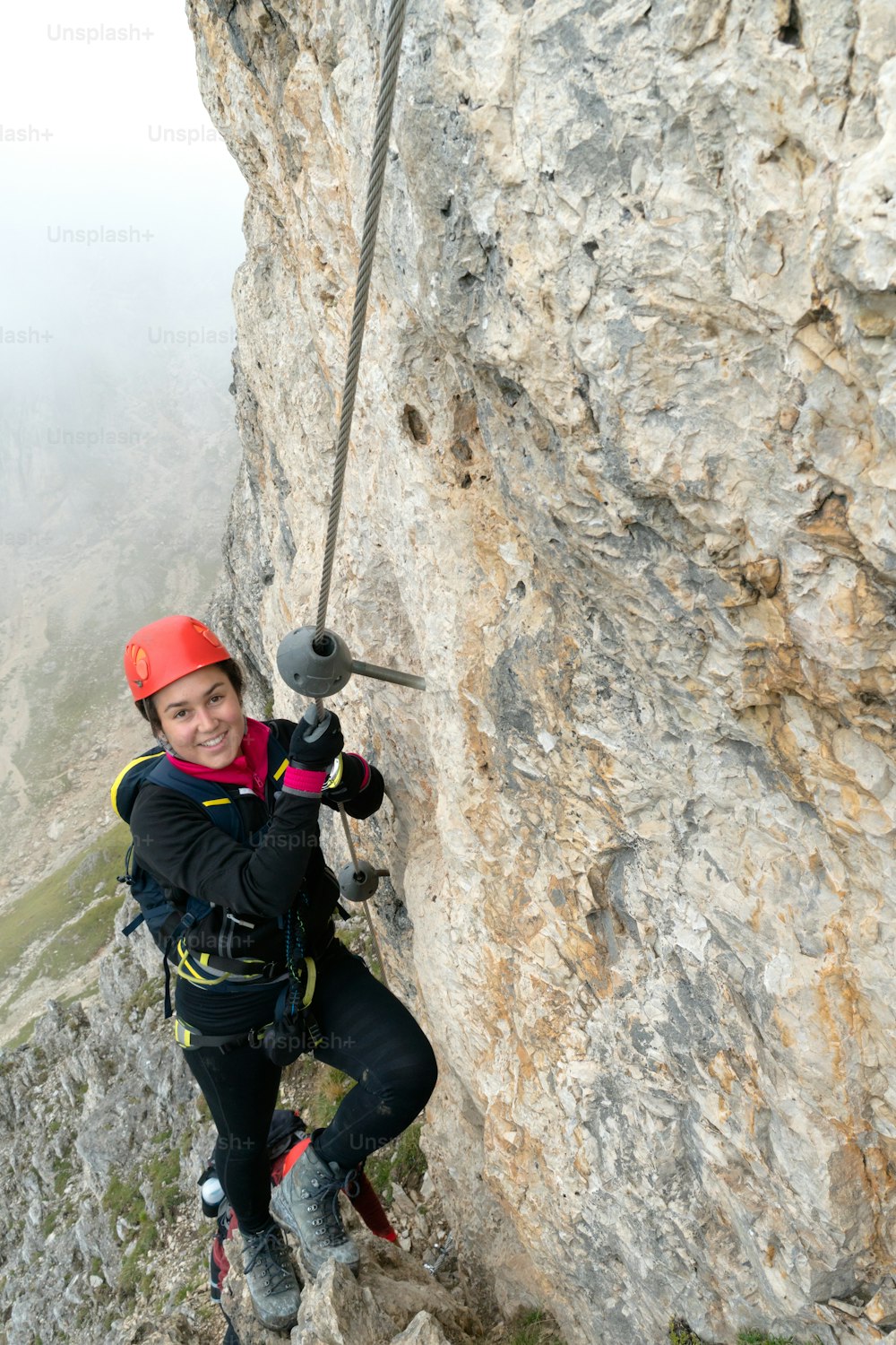 young attractive female mountain climber on a steep and exposed Via Ferrata in Alta Badia in the South Tyrol in the Italian Dolomites