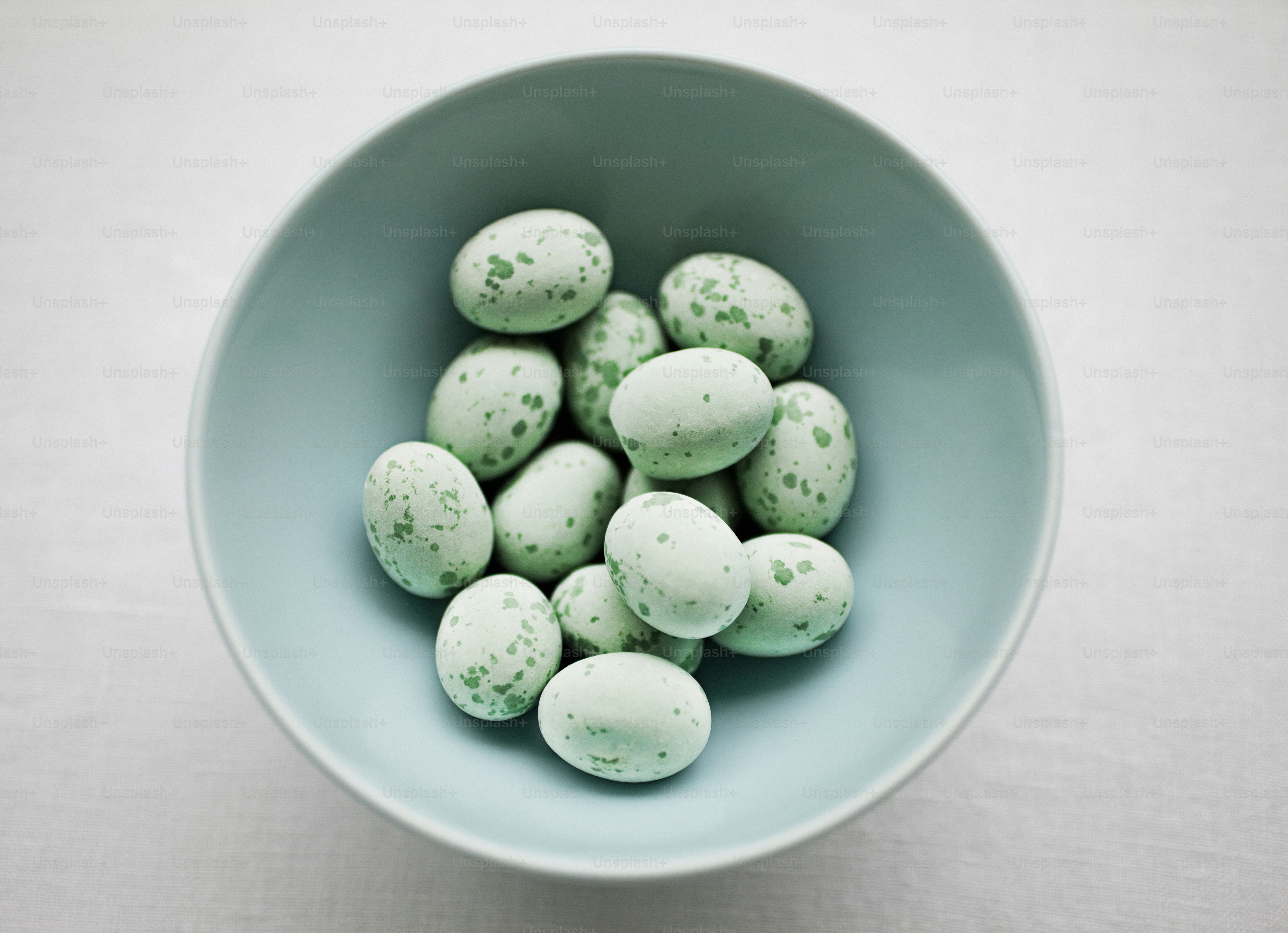 a blue bowl filled with green speckled eggs