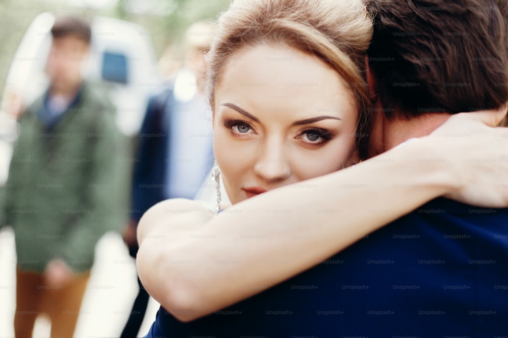 Happy newlywed bride hugging groom after wedding ceremony outdoors face close-up, newlywed couple portrait