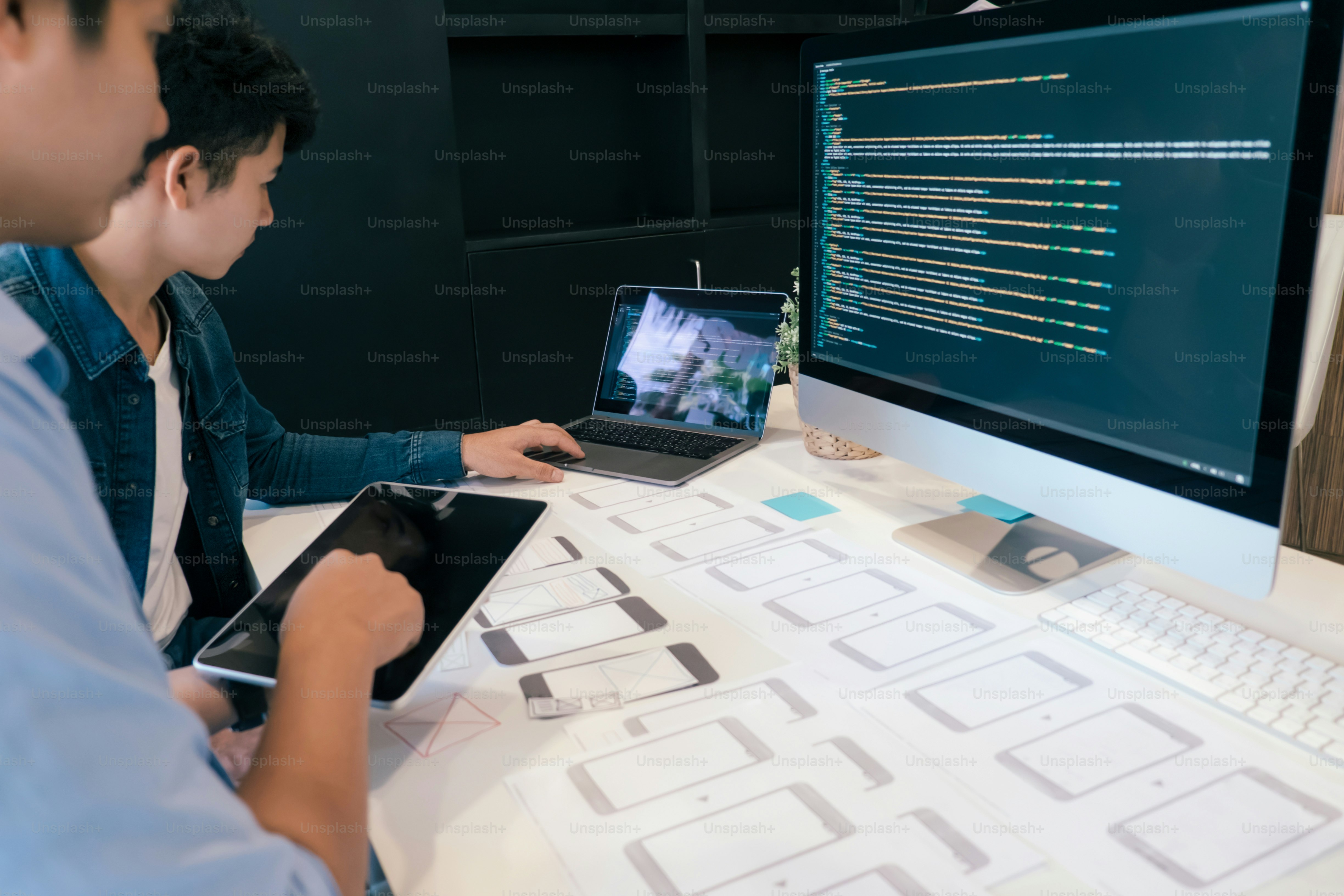 Two people working on mobile app wireframes at a desk with computers