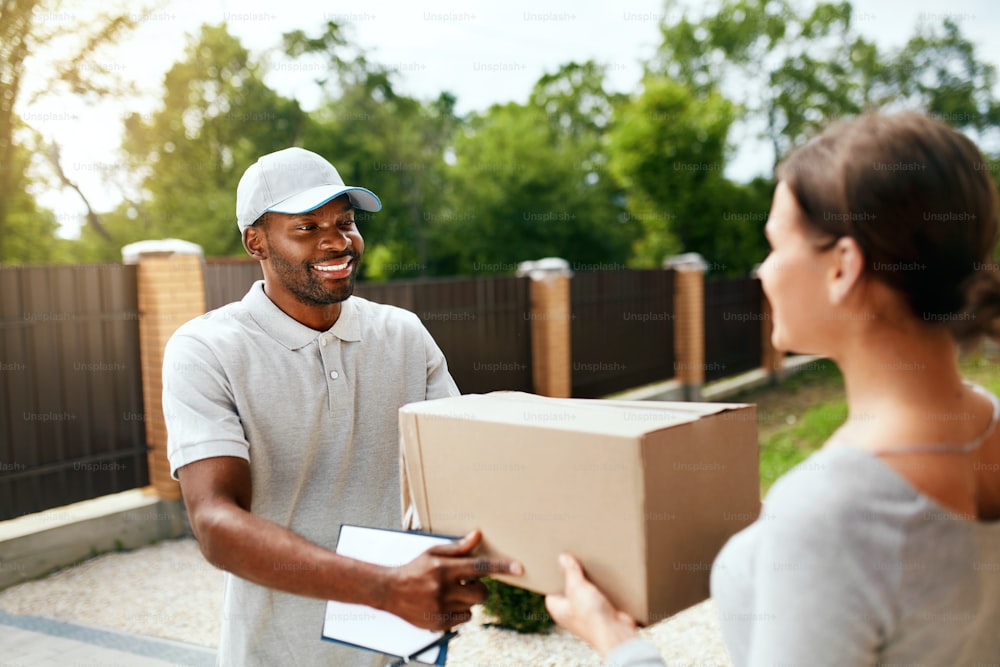 Package Delivering. Delivery Man Delivering Box To Woman Outdoors. Courier Service. High Resolution