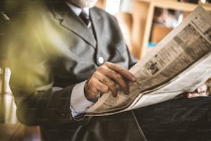 Senior man reading newspaper. Focus is on hand.