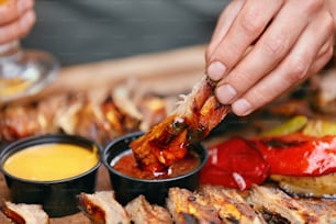 Barbecue Ribs With Sauсes Closeup. Man's Hand With Spareribs. High Resolution