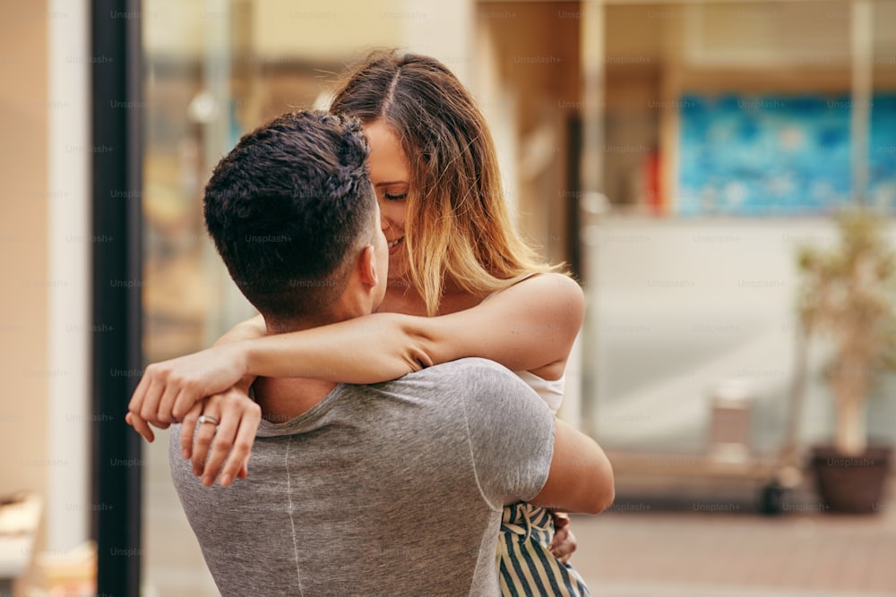 Jeune couple affectueux s’embrassant et partageant un baiser romantique tout en se tenant ensemble dans une rue de la ville