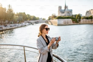 Junge Touristin, die während des Sonnenuntergangs in Paris vom Boot aus einen wunderschönen Landschaftsblick auf das Flussufer mit der Kathedrale Notre-Dame genießt