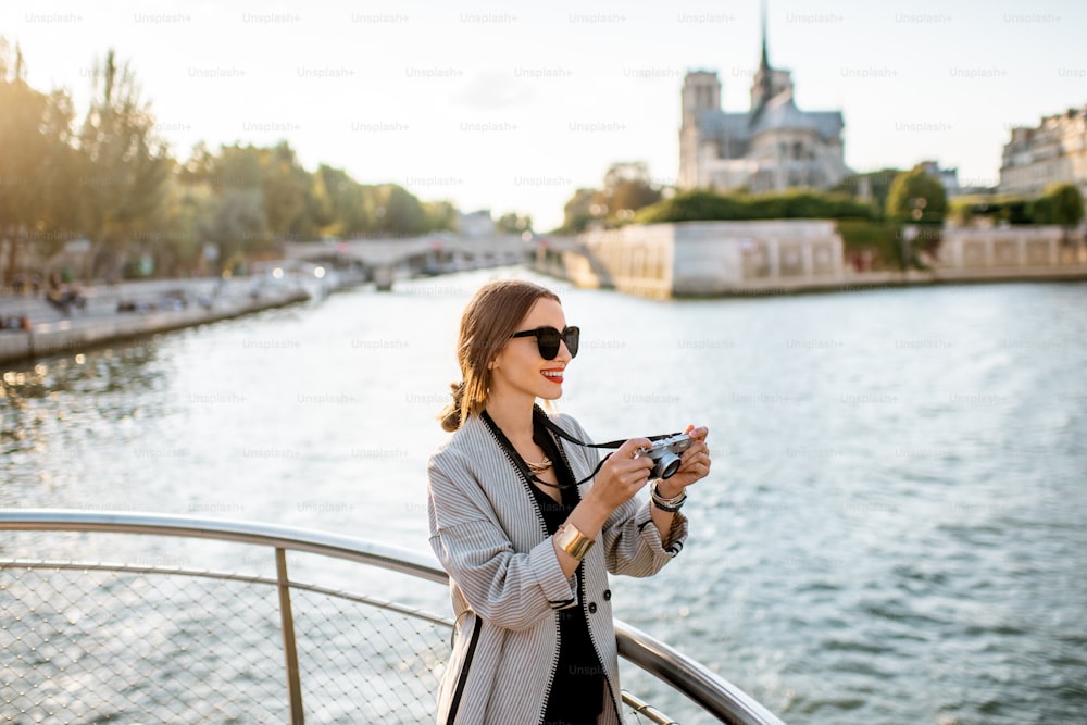 Young woman tourist enjoying beautiful landscape view on the riverside with Notre-Dame cathedral from the boat during the sunset in Paris