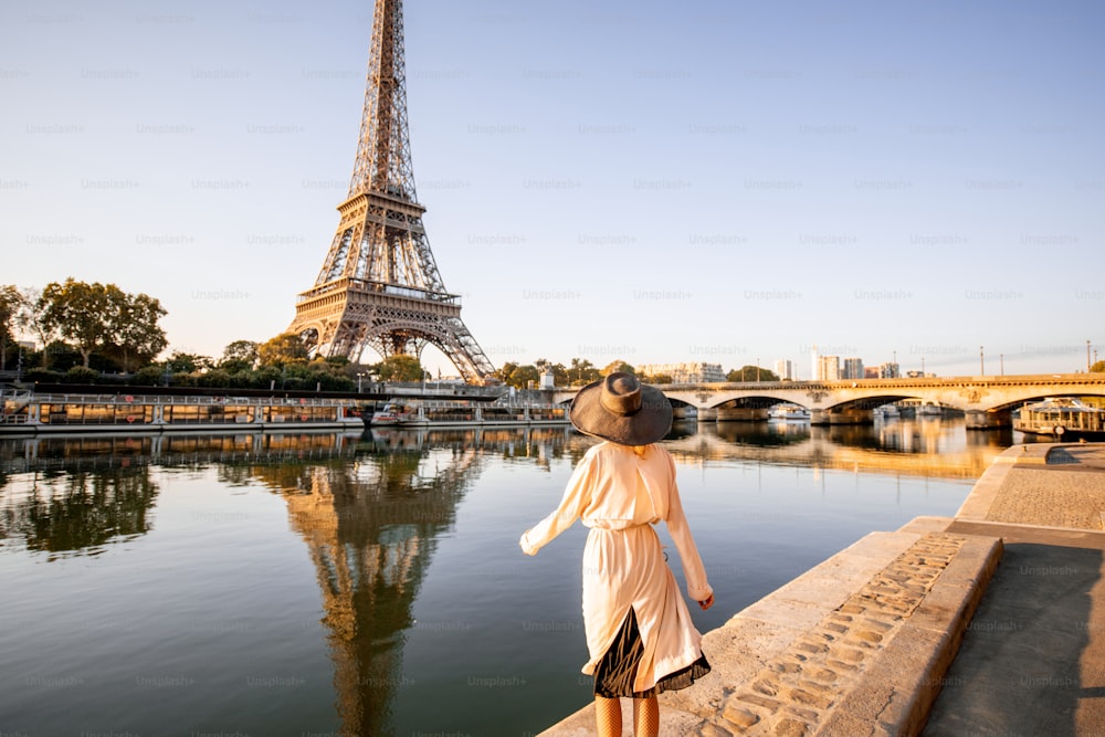 Junge Touristin genießt den Landschaftsblick auf dem Eiffelturm mit schöner Reflexion auf dem Wasser während des mornign Lichts in Paris
